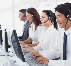 A group of people with headsets on working at computers.